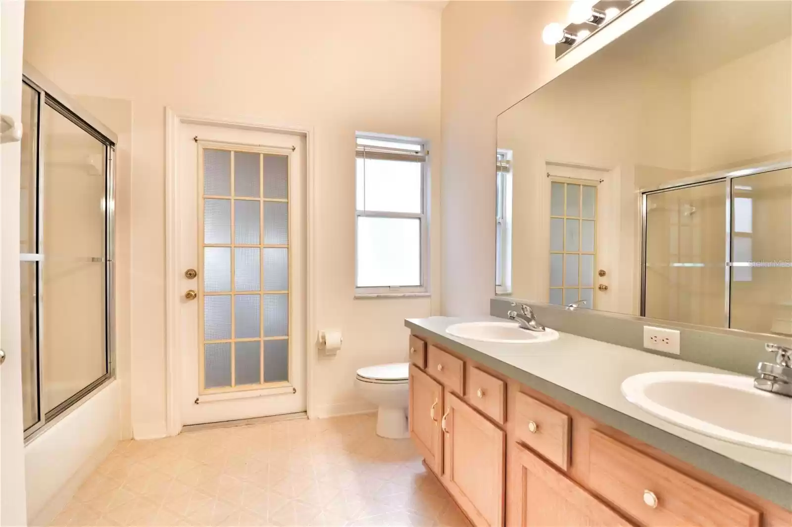 and a bathroom with a tub/ shower combo and dual sink vanity