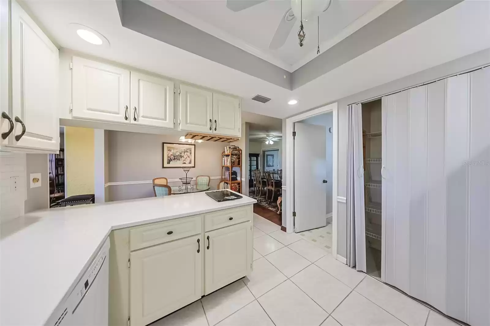 Kitchen is updated with tile flooring and includes lots of solid wood cabinetry, as well as large pantry seen to the right in this photo.