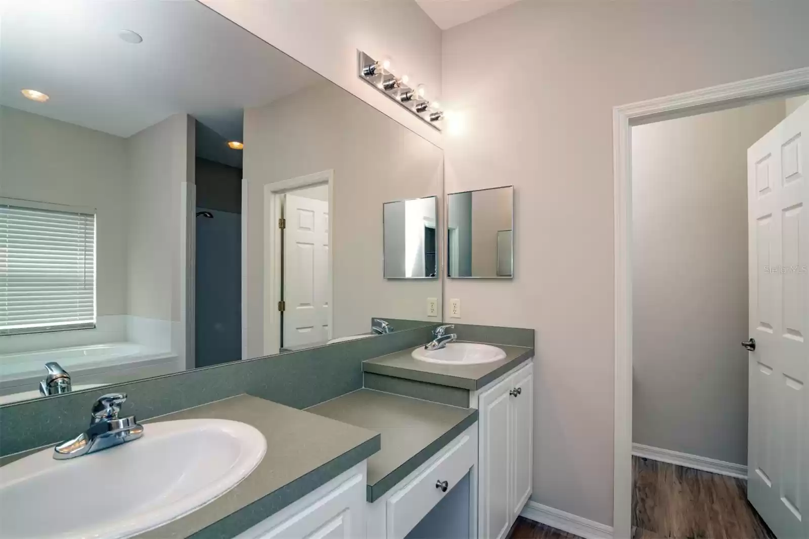 Double vanities with makeup area in the center and door opening to private water closet