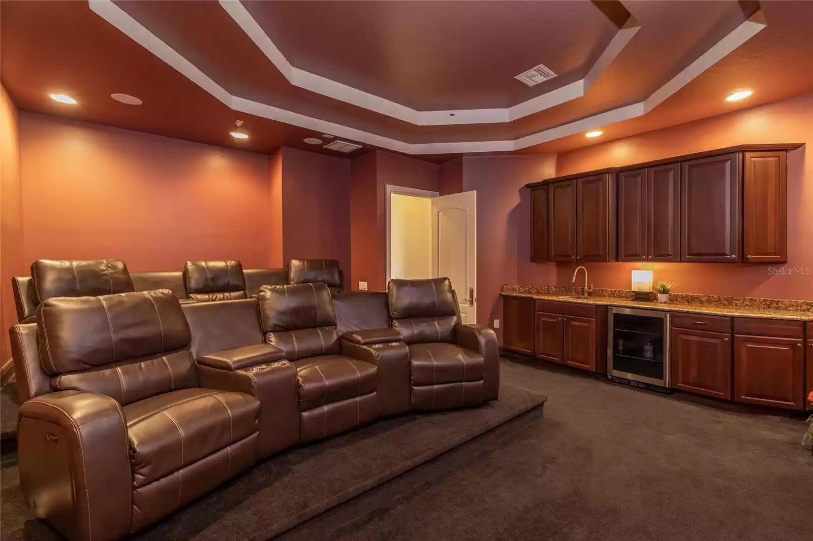 Theater room with wet bar and beverage refrigerator.