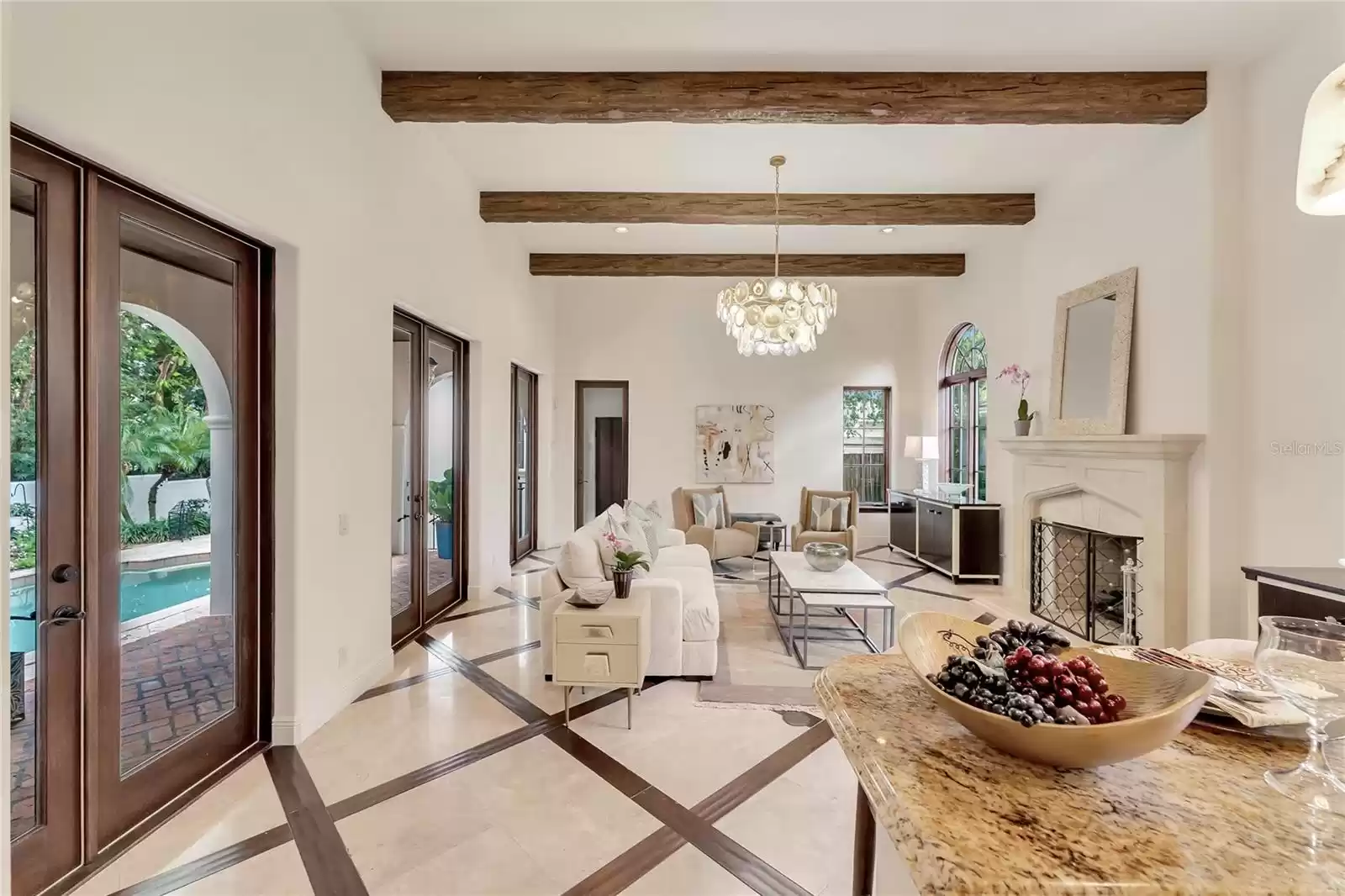 Kitchen opens to gathering room with Cypress beams, stone fireplace