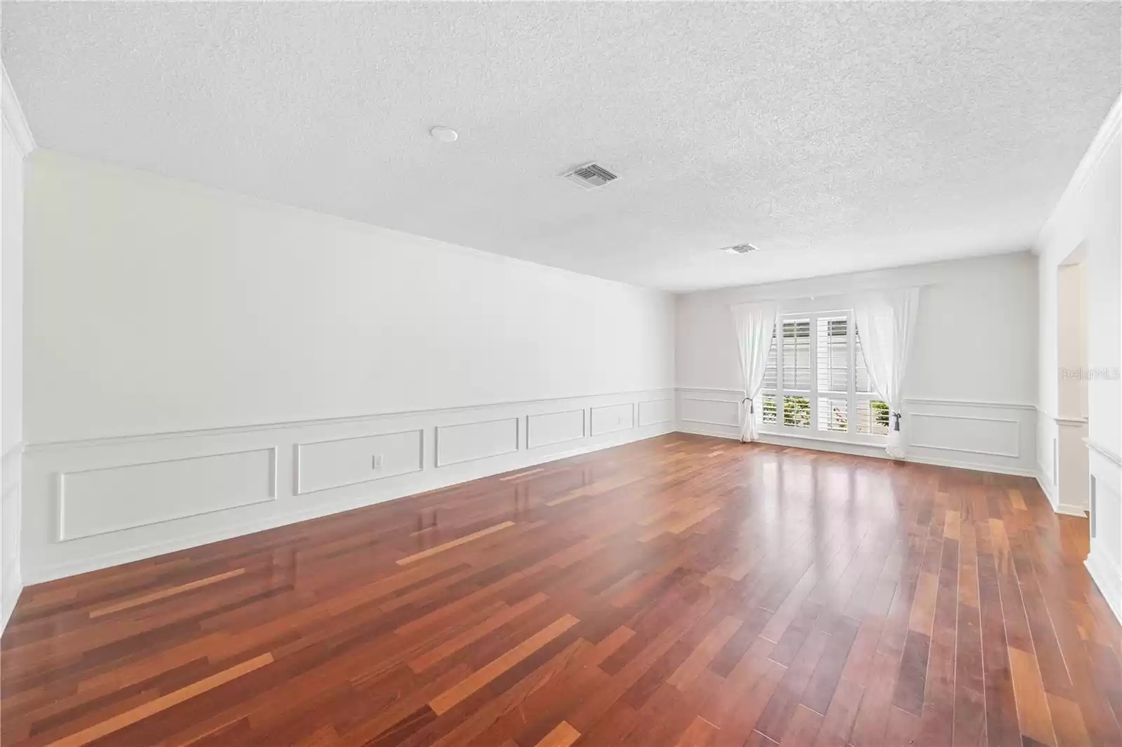 Living room/dining room combo with wainscoting and Plantation shutters.