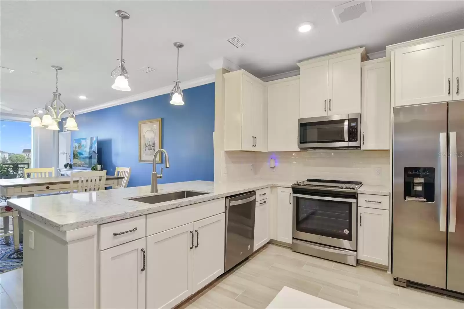 The home chef will be delighted with the modern SHAKER STYLE CABINETRY, stainless steel appliances, decorative backsplash, STONE COUNTERS and the breakfast bar under pendant lighting connects it all seamlessly to the open living and dining.