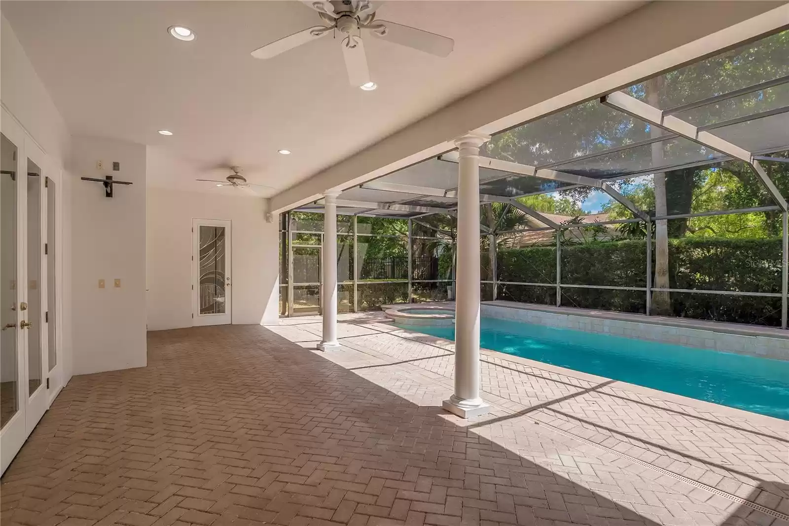 Expansive covered lanai with chevron pattern laid pavers.