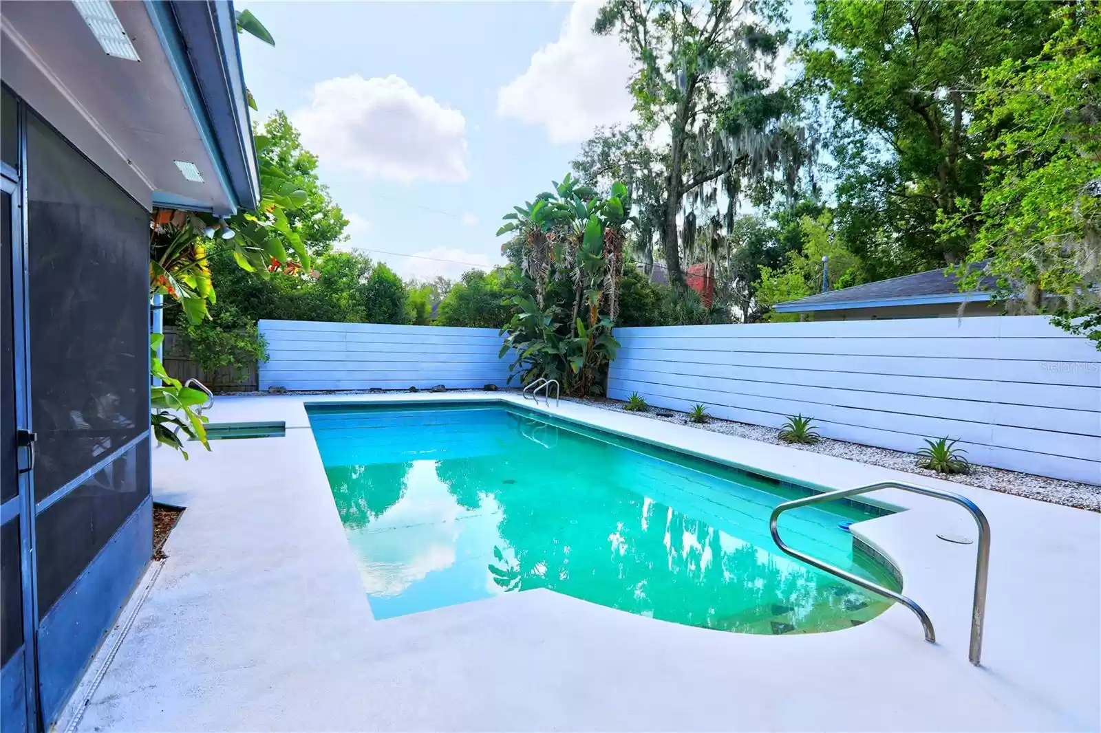 Oversize pool with spa, privacy fence and tropical landscape