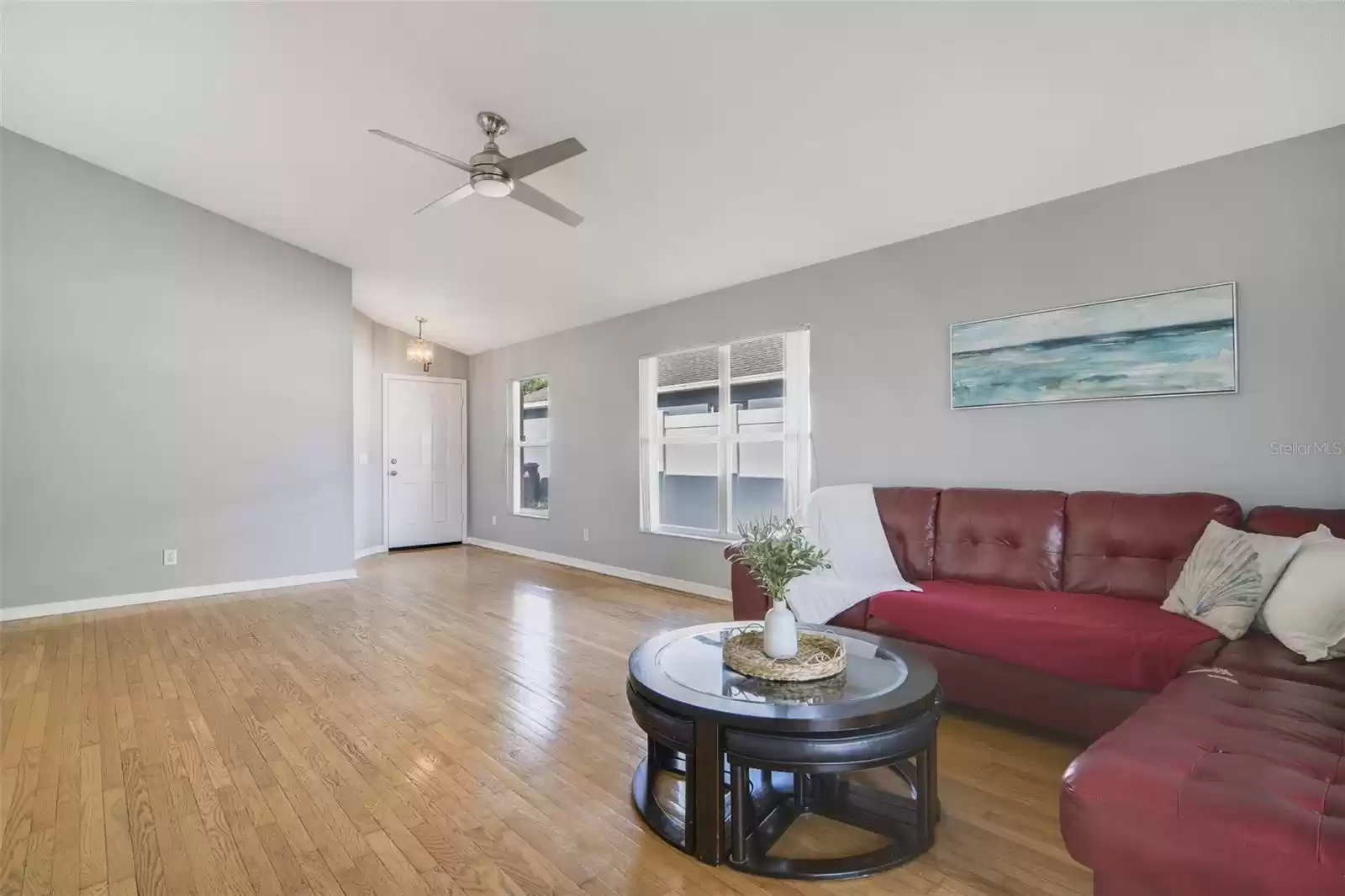 Step through the front door and into a versatile formal living and dining area featuring WOOD FLOORS, a VAULTED CEILING and sliding glass door access to the covered lanai overlooking the screened pool.