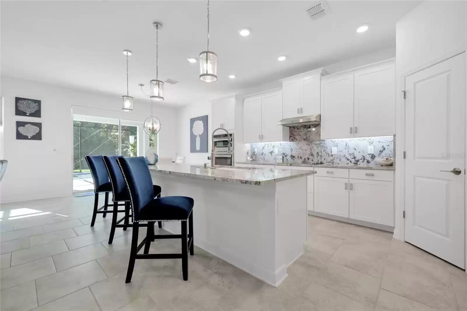 The gorgeous kitchen overlooks a casual dining space and generous family room complete with a stylish accent wall and sliding glass door access to the lanai, outdoor kitchen and HEATED/SCREENED POOL!