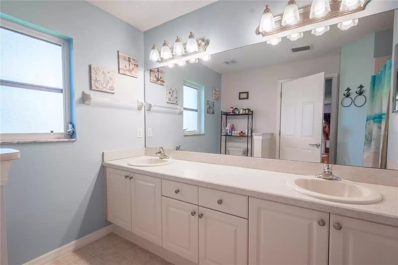 The primary bath features a mirrored vanity with dual sinks, storage and down light fixtures.