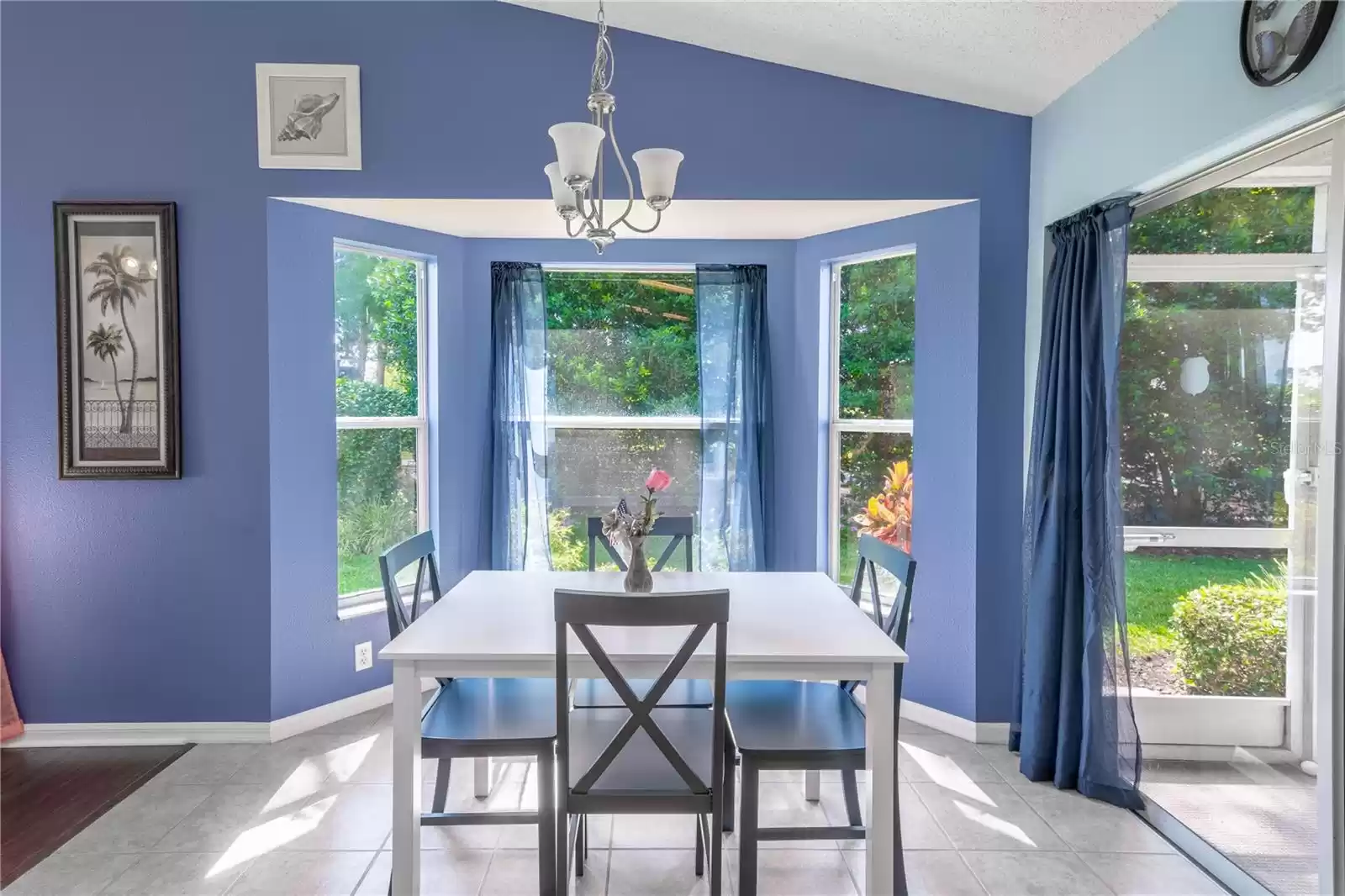 The breakfast nook sits beneath a chandelier in a bay window