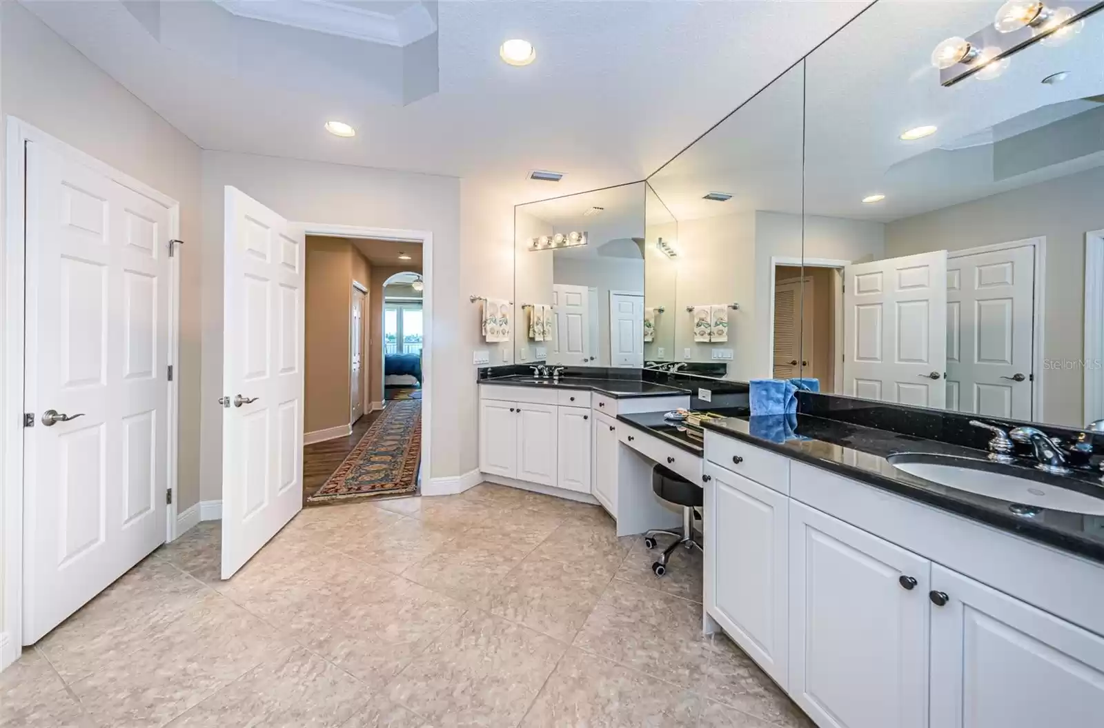 ... Master / Primary Bathroom Suite Looking Out Toward Hallway. Double Vanity Area with Makeup Station in the Middle. Plenty of Closet Space. Privacy Room On Left with Closed Door.