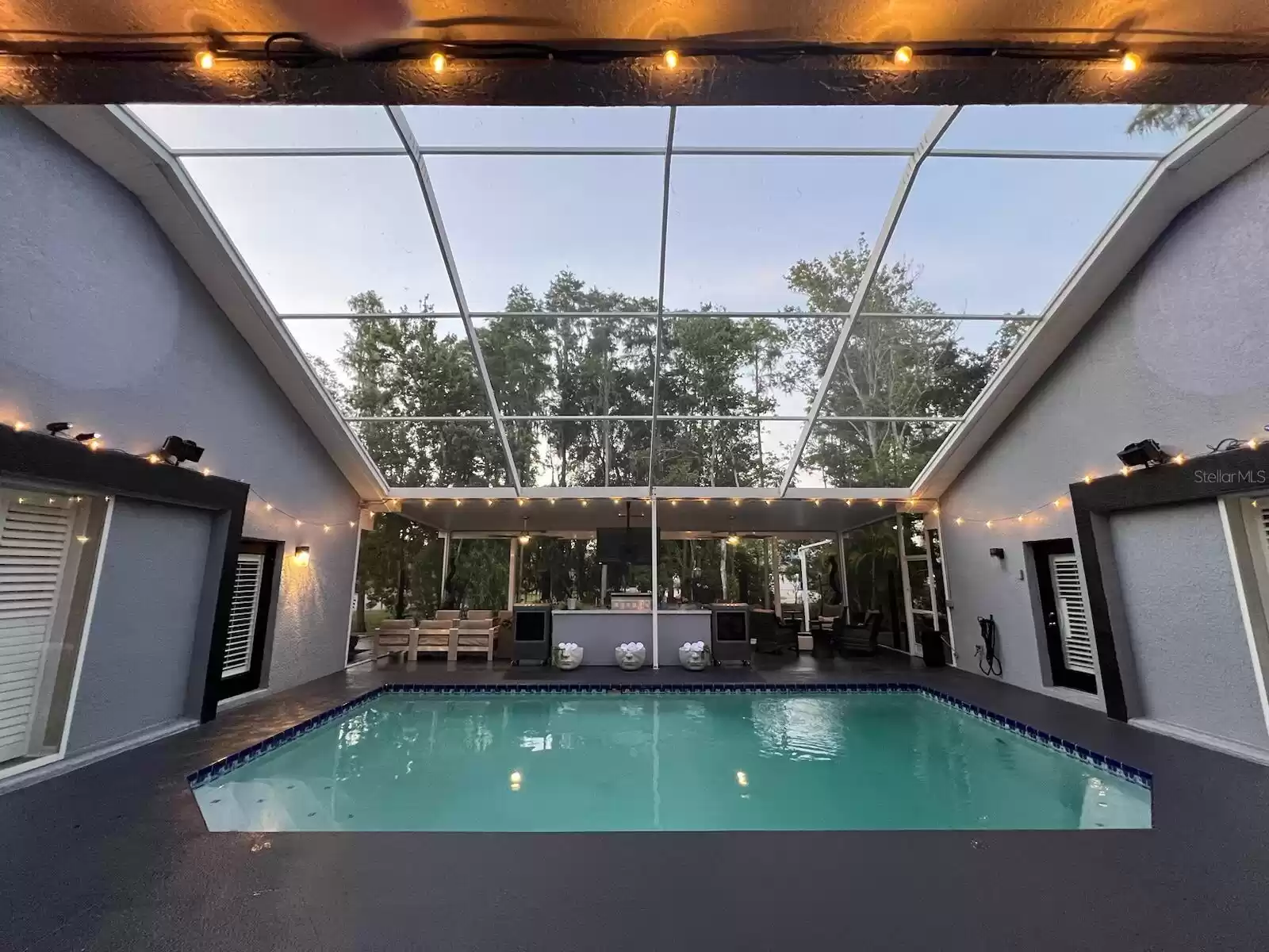 Upward view of of lighting over the private salt treated, heated poll. This area can be accessed from the home via the living room as seen here, the primary bedroom to the right and guest bedroom with full bath to the left. Then move to the covered lanai ahead for relaxing, cooking and dining and more