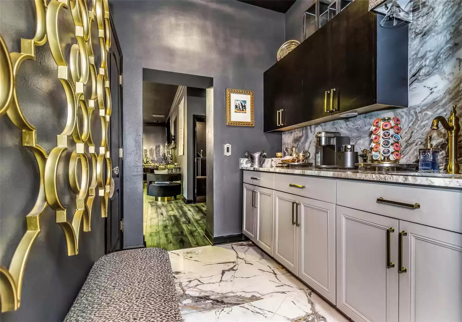 Efficiently equipped Butler Pantry with plenty of storage, granite counter, polished porcelain wall and floor. Notice the view into the adjoining bar