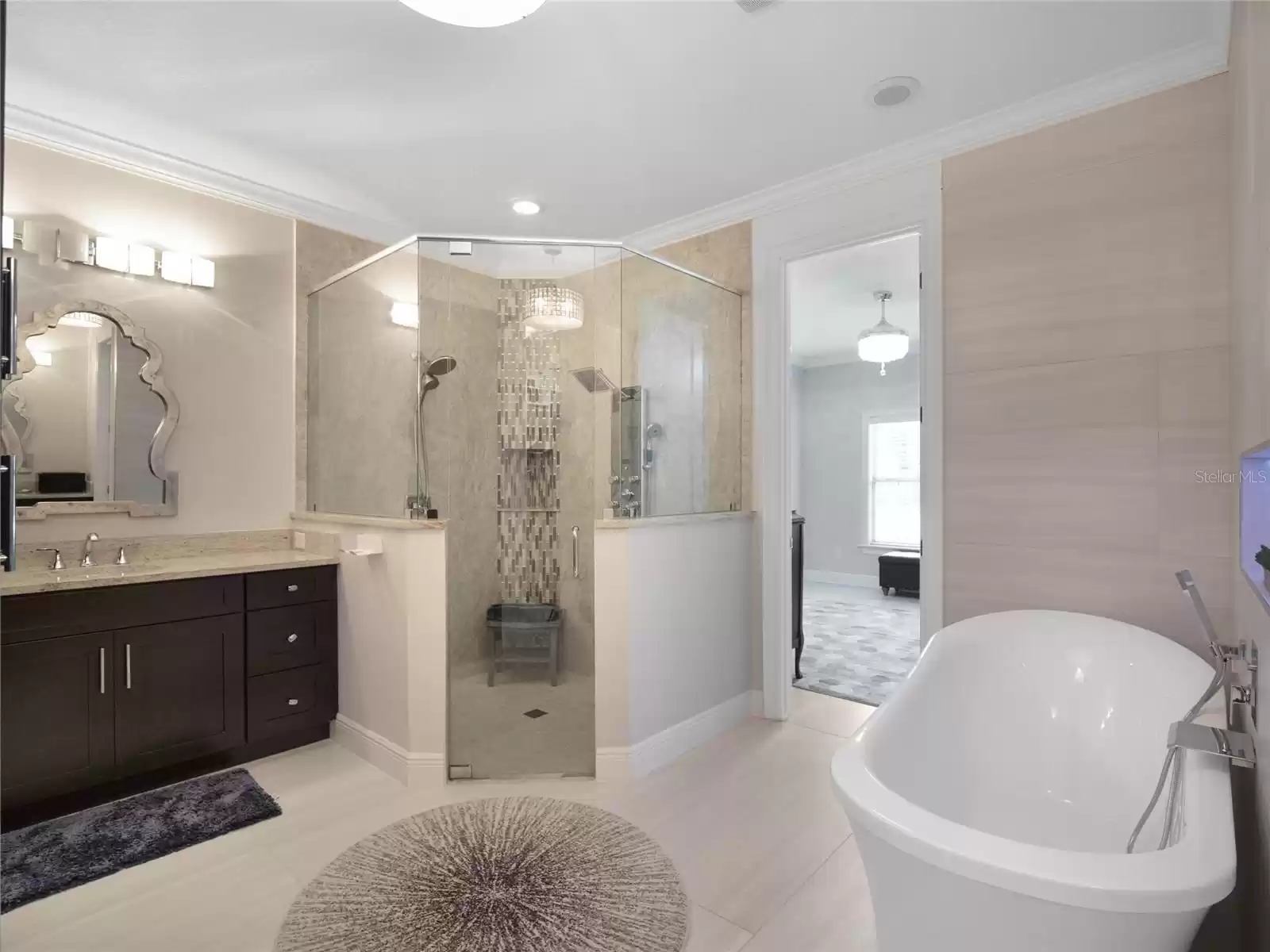 Primary bathroom featuring separate vanity areas and spacious shower and soaking tub leads in to the custom built in closet.