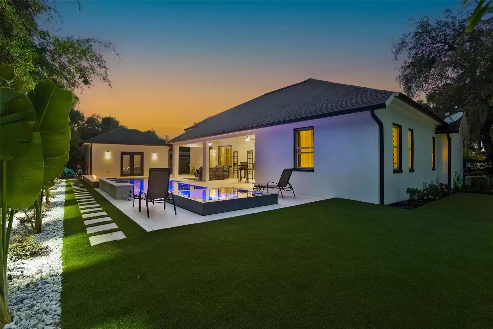 Backyard artificial turf and pool at twilight.