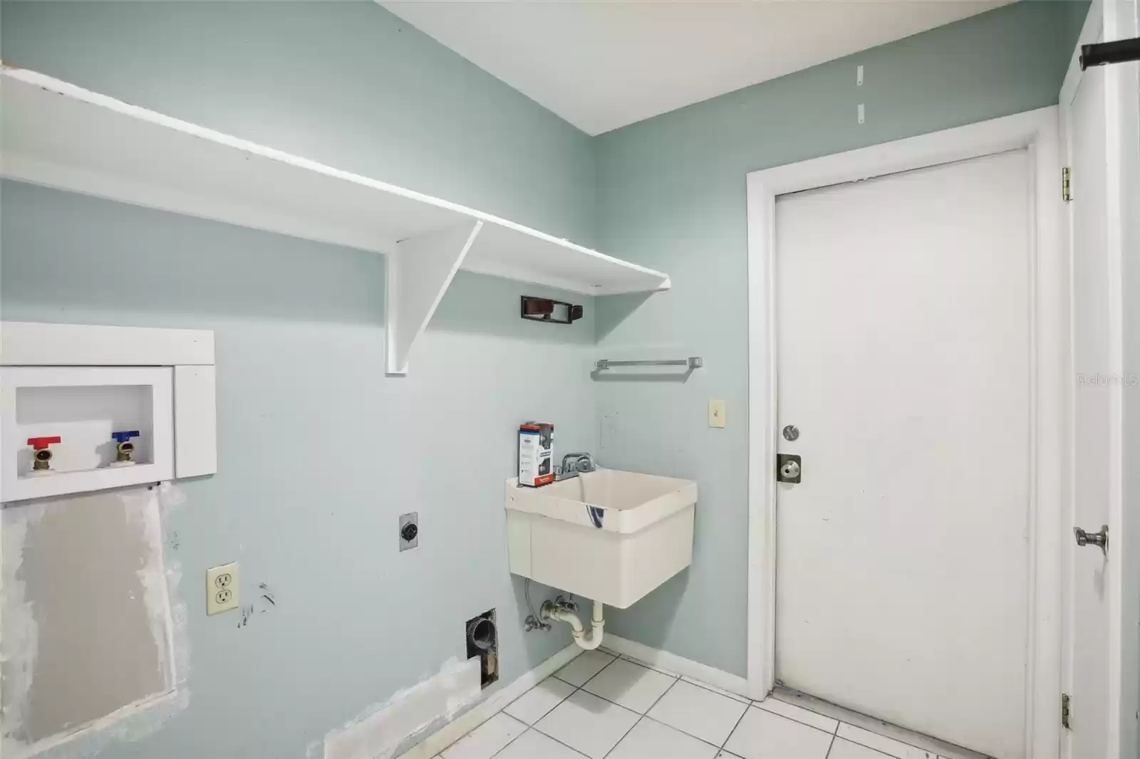 Inside laundry area with utility sink and closet leads to garage