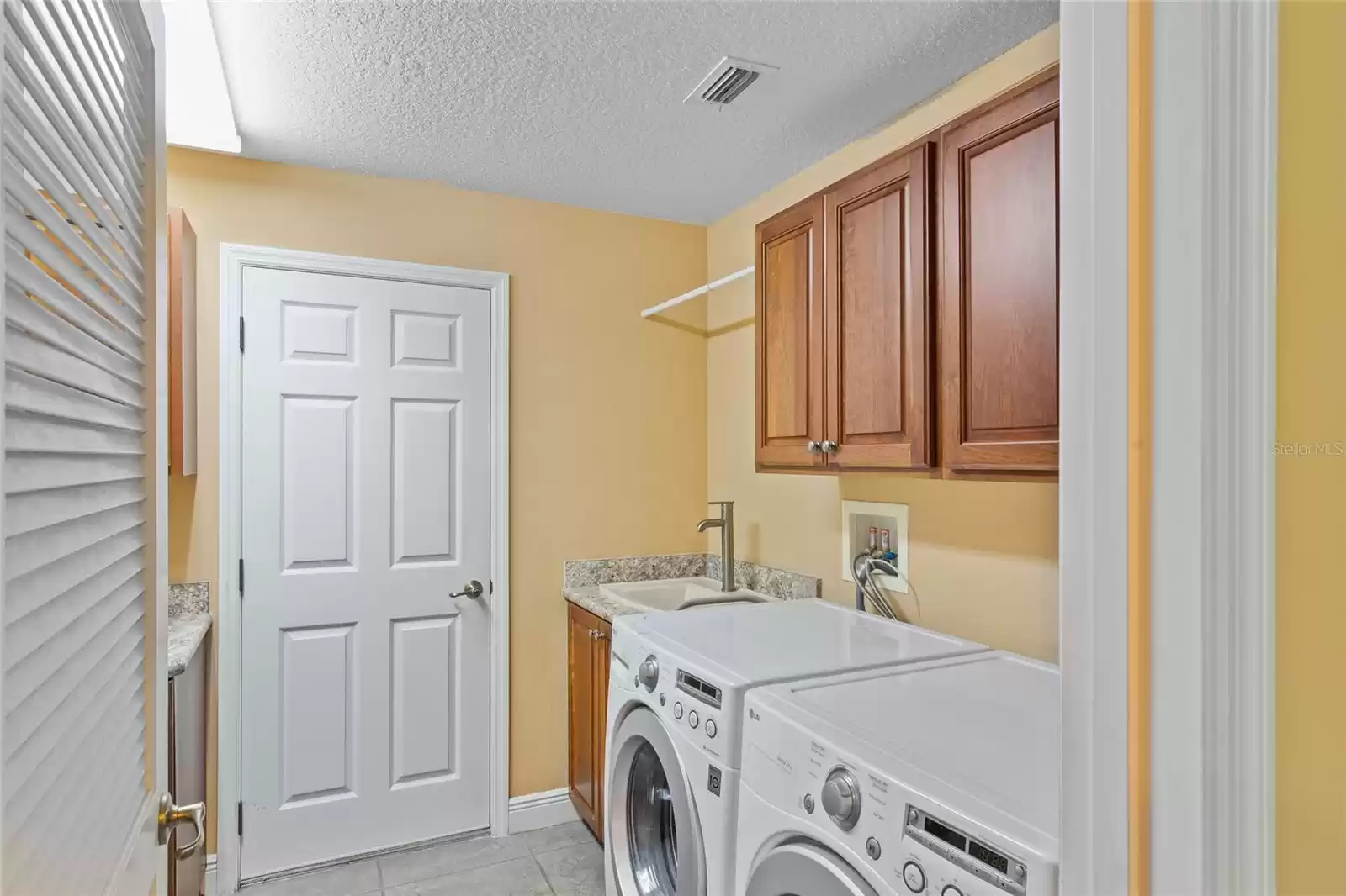 Laundry room complete with washer and dryer, extra sink and cabinets