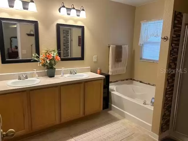 Primary bathroom with double sinks, garden tub with window and shower.