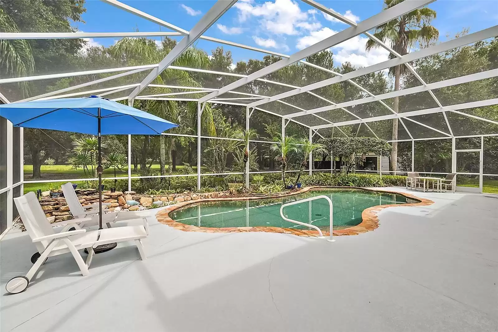 While sitting under the covered patio, you see views of the pool and the nearly two-acre backyard.