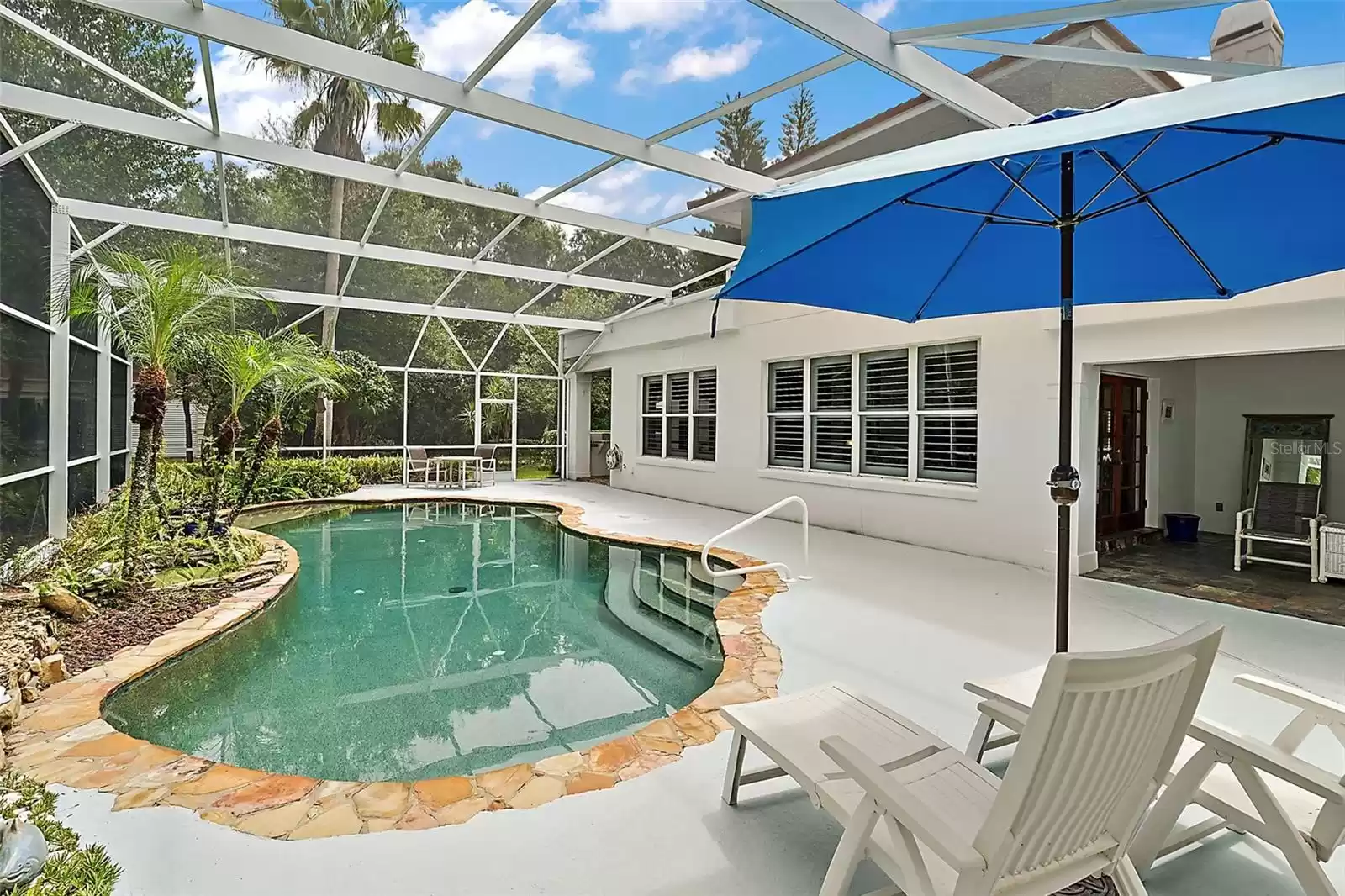 Relax in the Florida sun. The screen-enclosed heated, salt water pool is surrounded by a natural stone, replicated on several walkways around the home.