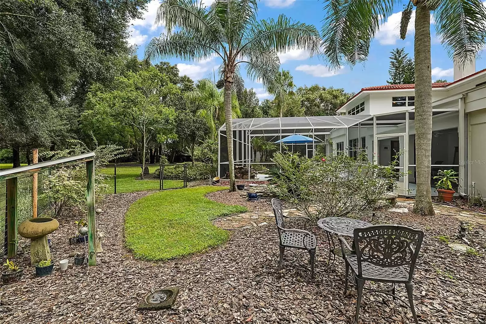 This charming outdoor space features a fenced area perfect for a dog walk, surrounded by lush greenery and a peaceful rose garden.