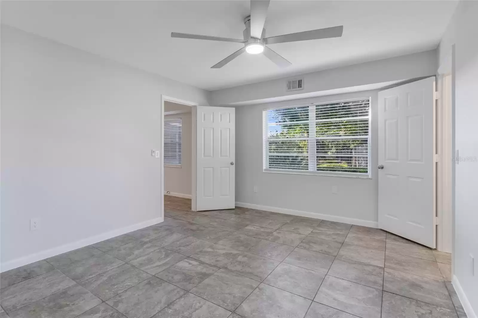 Master bedroom with newly painted walls, ceiling fan and large walk in closet.