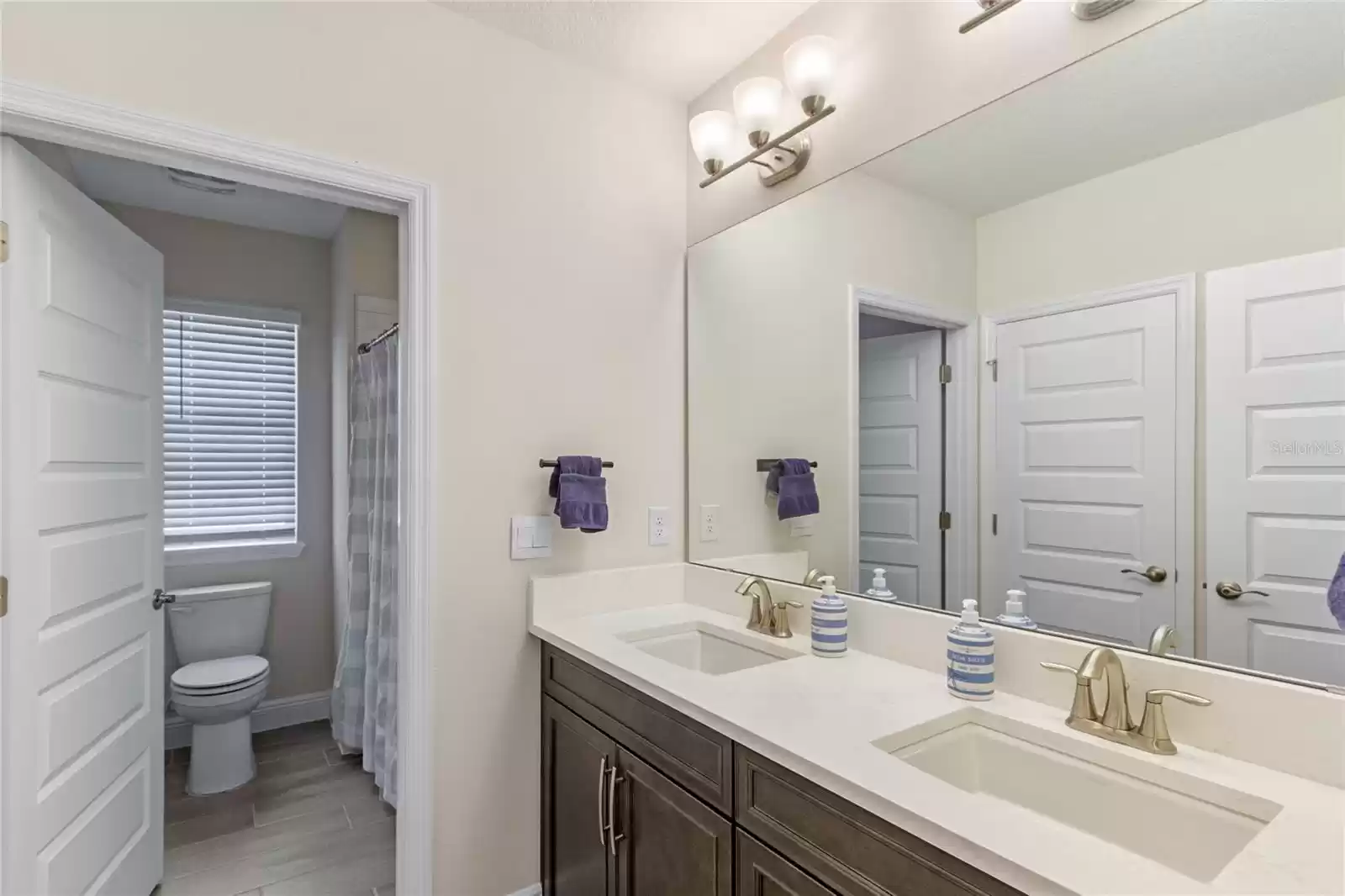 Secondary bath with dual sinks,  private shower and toilet area.