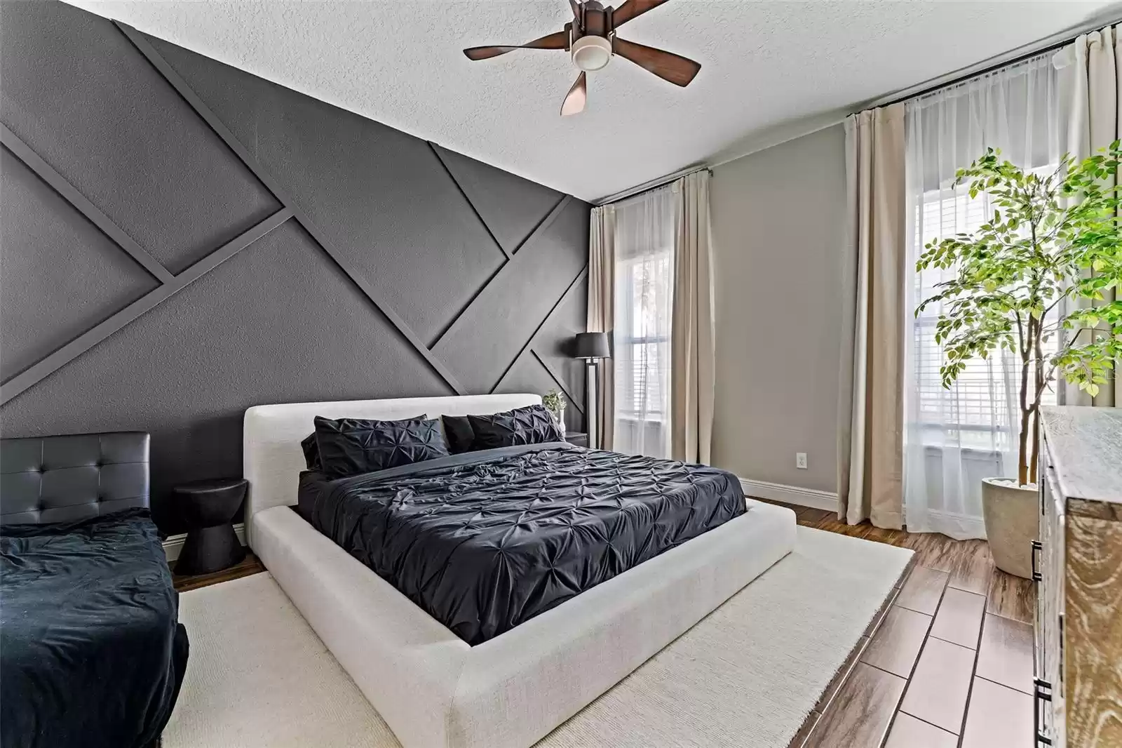 Primary bedroom with accent wall and ceiling fan.