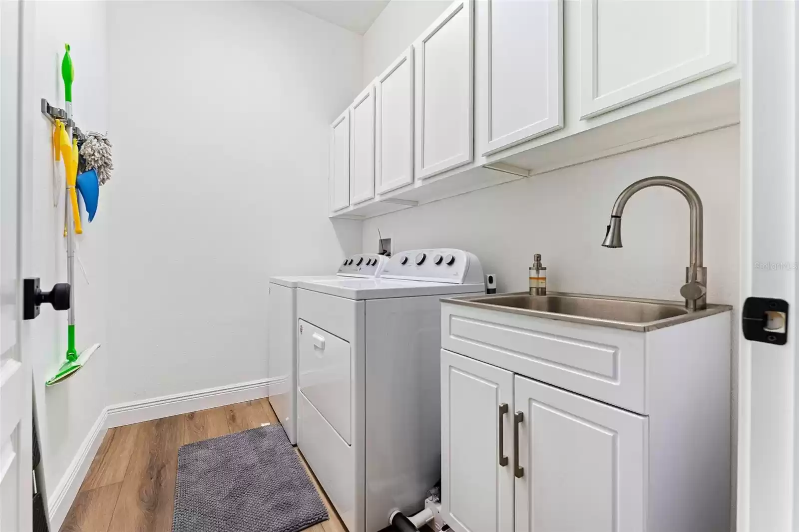 Laundry room with washer and dryer provided as tenant courtesy, plus a wash sink.