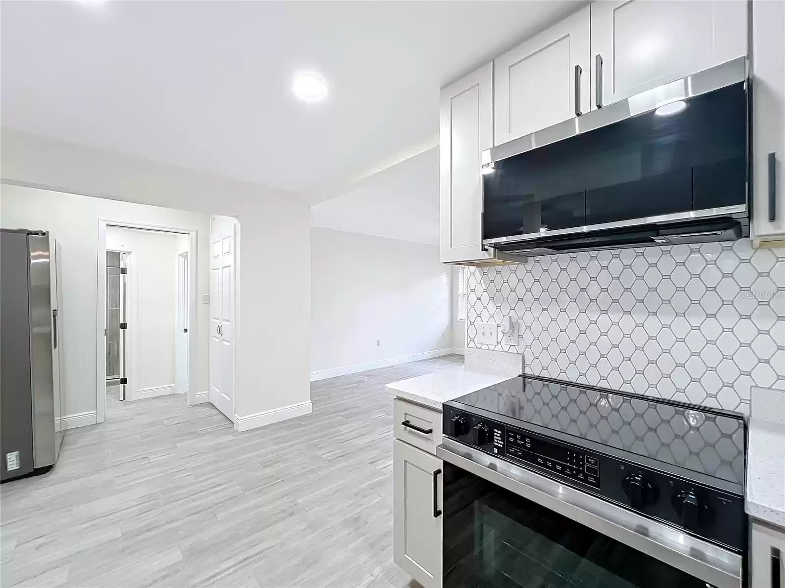 View of pantry & fridge (& passage to primary suite)