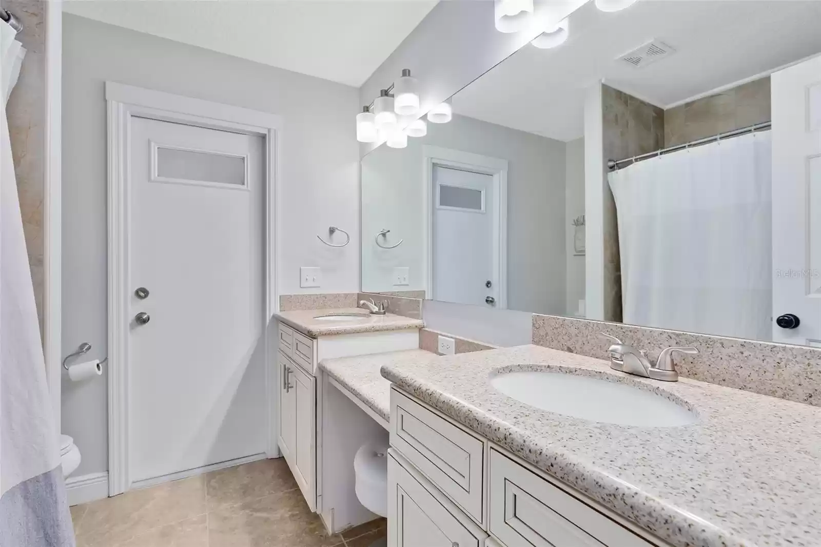 The beautifully appointed secondary bath is equipped with dual sinks, ample counter space, and access to the lanai.