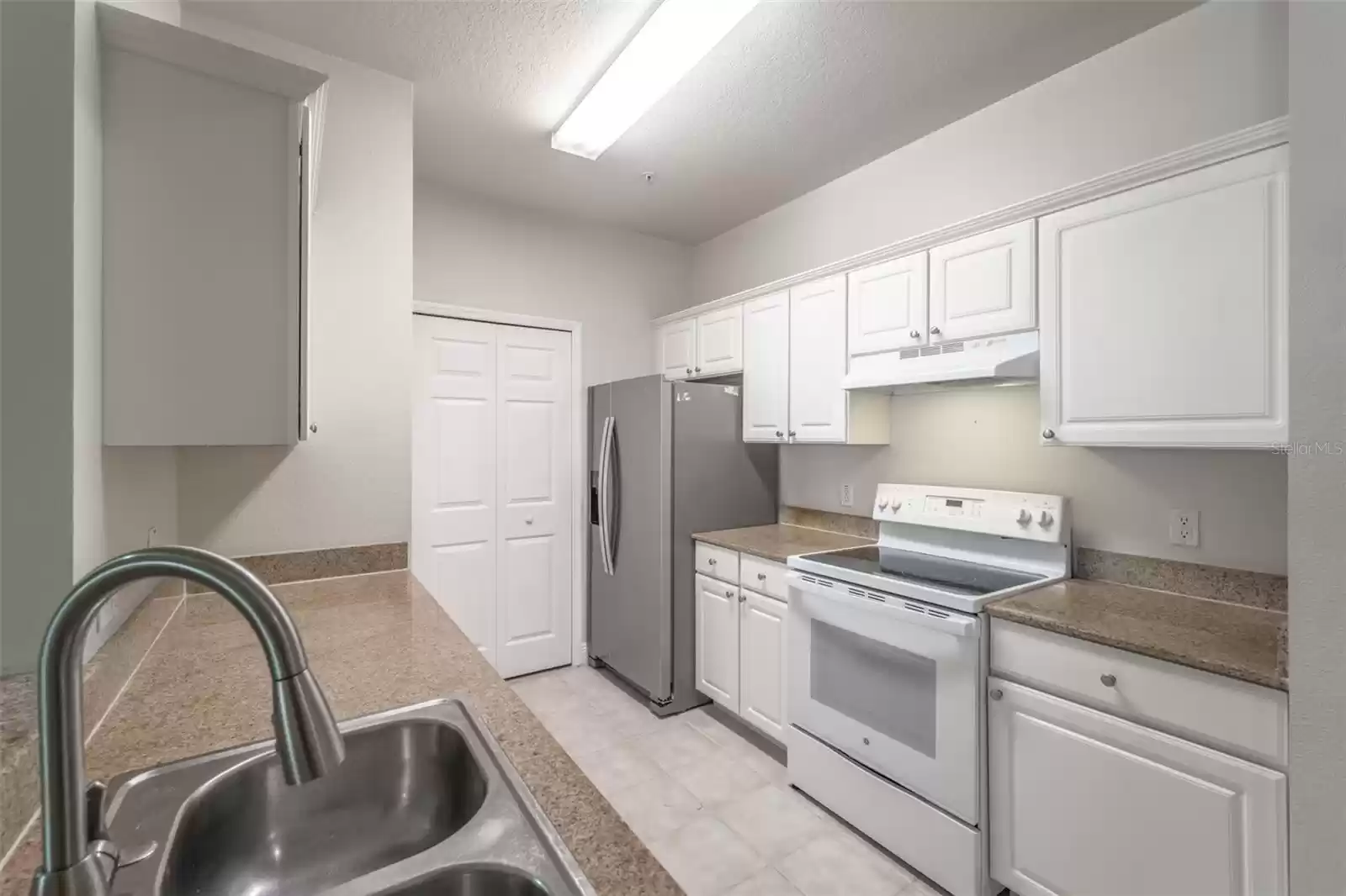 Stone countertops, stainless steel refrigerator & in-unit laundry room off the kitchen