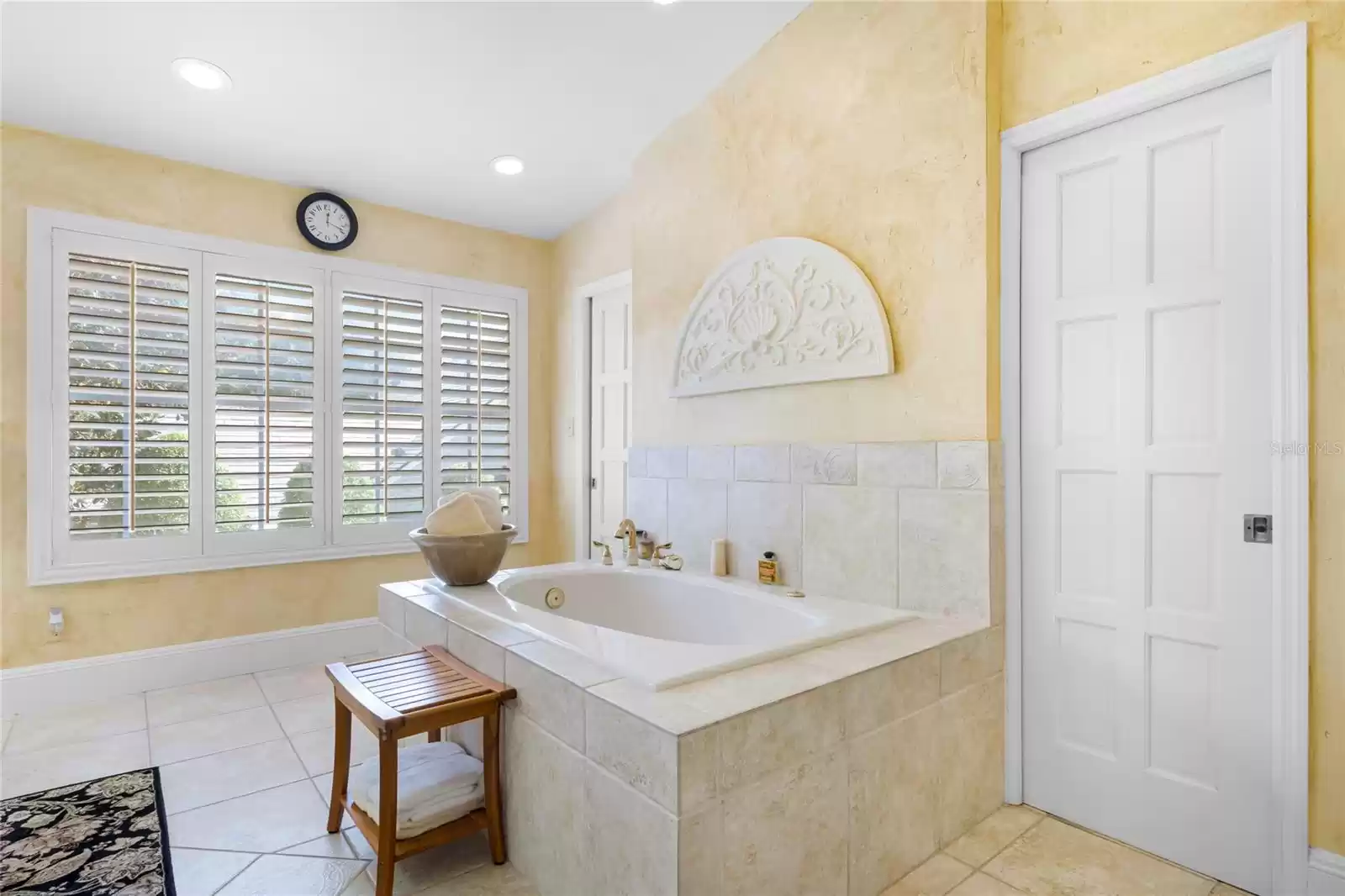 Jetted spa tub flanked by pocket doors of the spacious walk-in closet