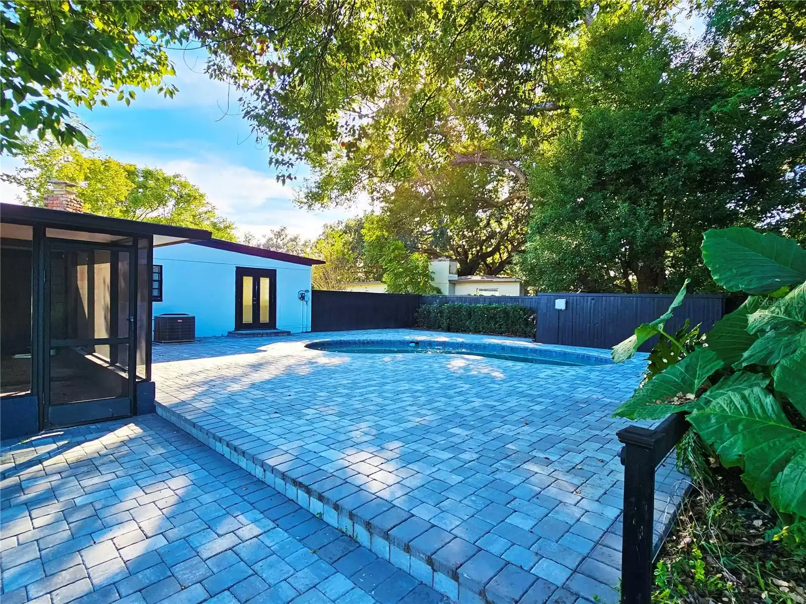 View of paver pool deck and screen enclosed patio