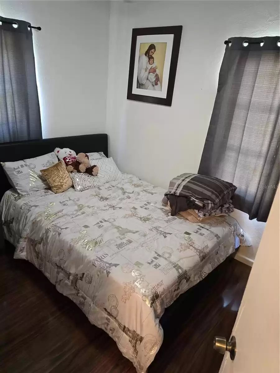 Guest bedroom with wood laminate and flooring throughout the house and 2 windows.