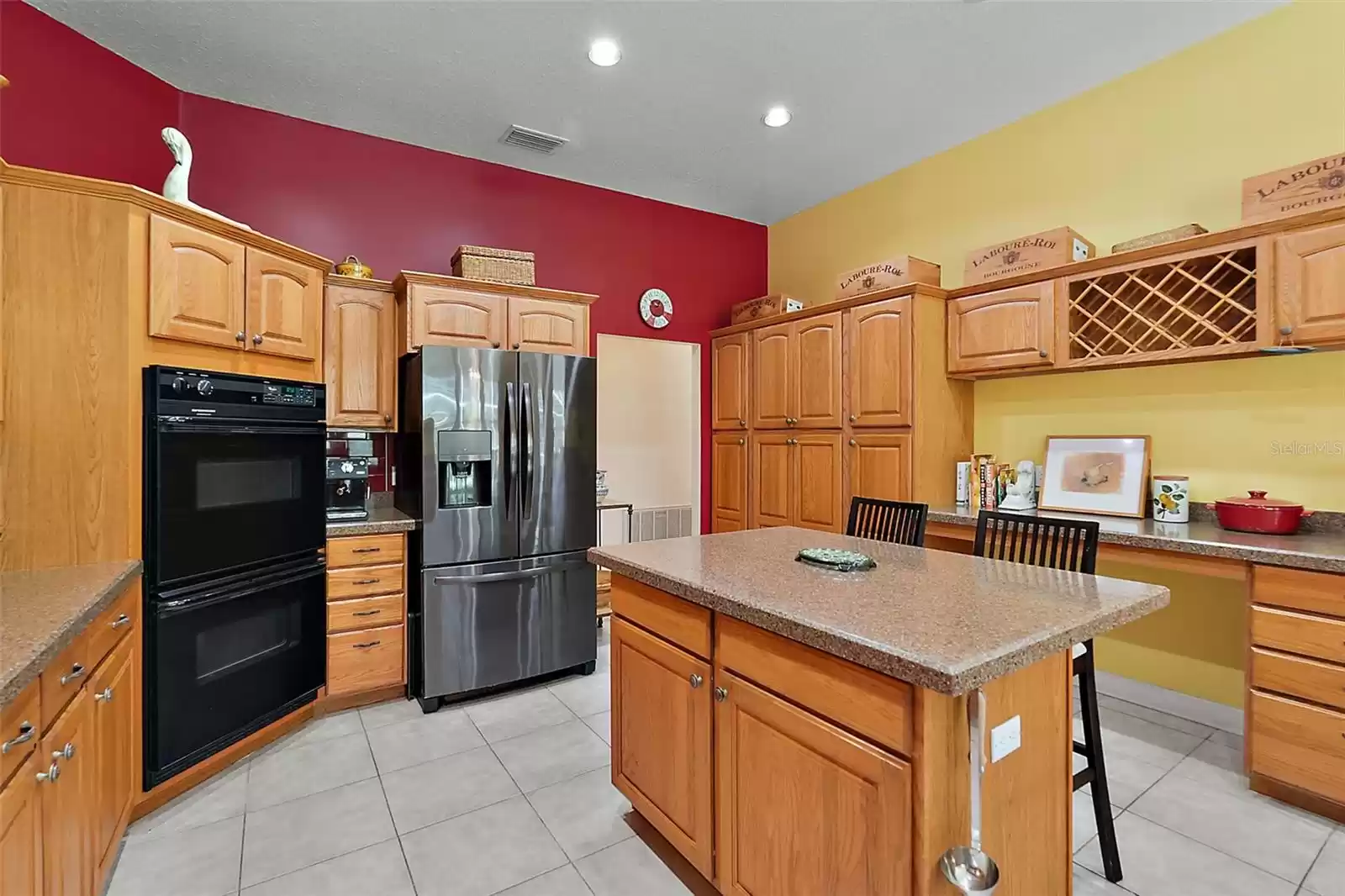 The island's stone countertop adds to the ample counter space. Solid wood cabinets surround the abundant kitchen. Double ovens, kitchen desk, large pantry, and wine storage make this an impressive working kitchen.