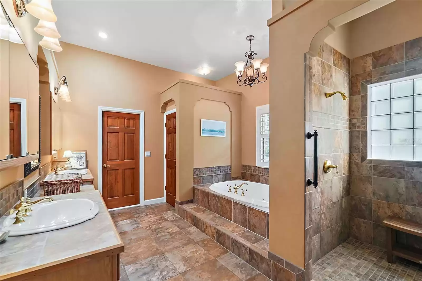 The owner's bath includes beautiful ceramic tiles throughout,  two sinks, a vanity space, a spa tub, with separate shower and water closets