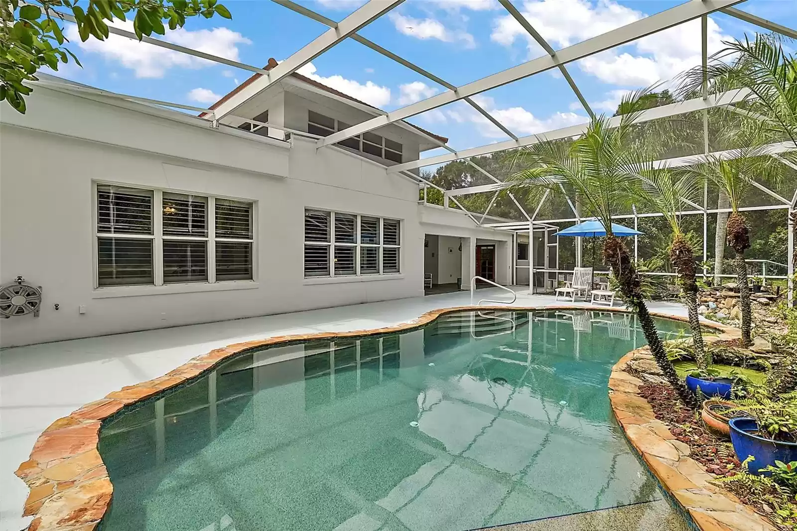 This view shows the breakfast nook and family room windows, covered patio, and owner's suite entrance from the pool's planters.