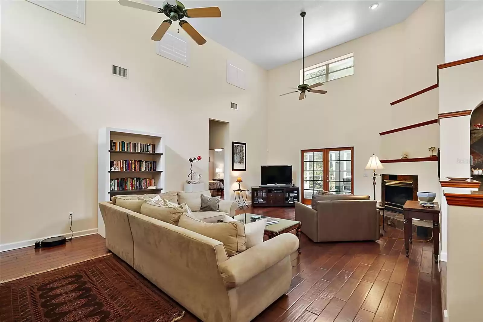 Expansive living room, where natural light pours in, highlighting the beautiful hardwood floors, fireplace, and soaring 17.5-foot ceilings.