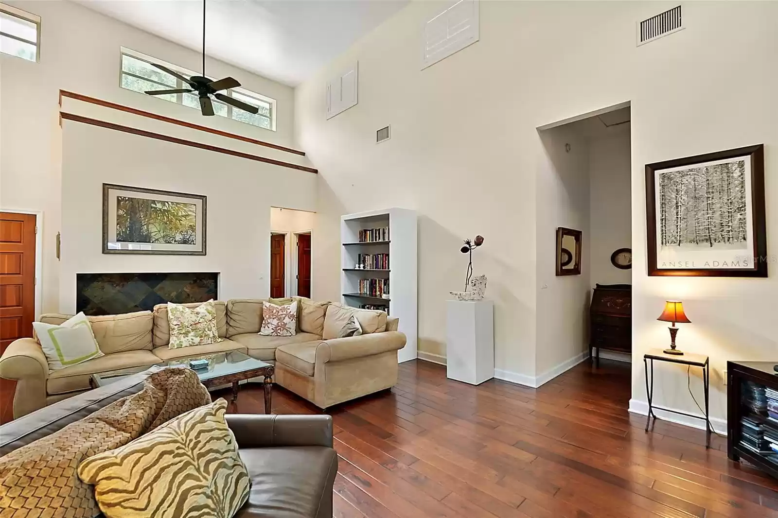 This living room view looks back toward the primary and secondary bedrooms. Ceiling fans and shutters keep the home cool from the heat of the western afternoon sun.