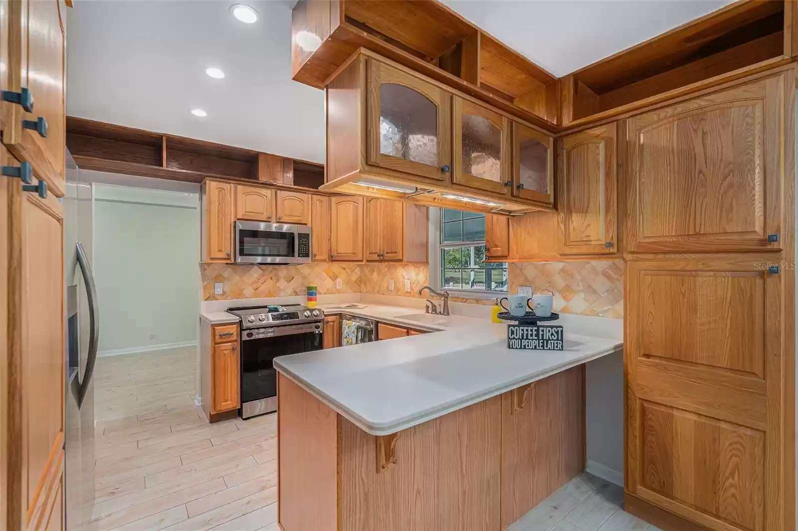 Kitchen features plentiful storage, breakfast bar and window overlooking pool, yard and golf course