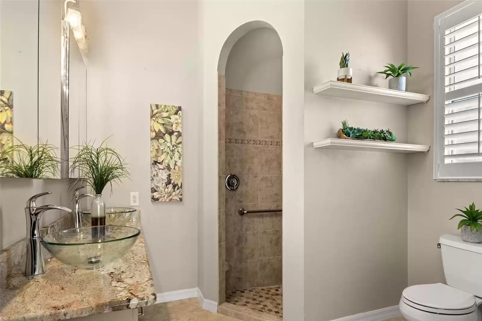 The ensuite bathroom has a ROMAN SHOWER and a dual sink vanity with GRANITE countertops.