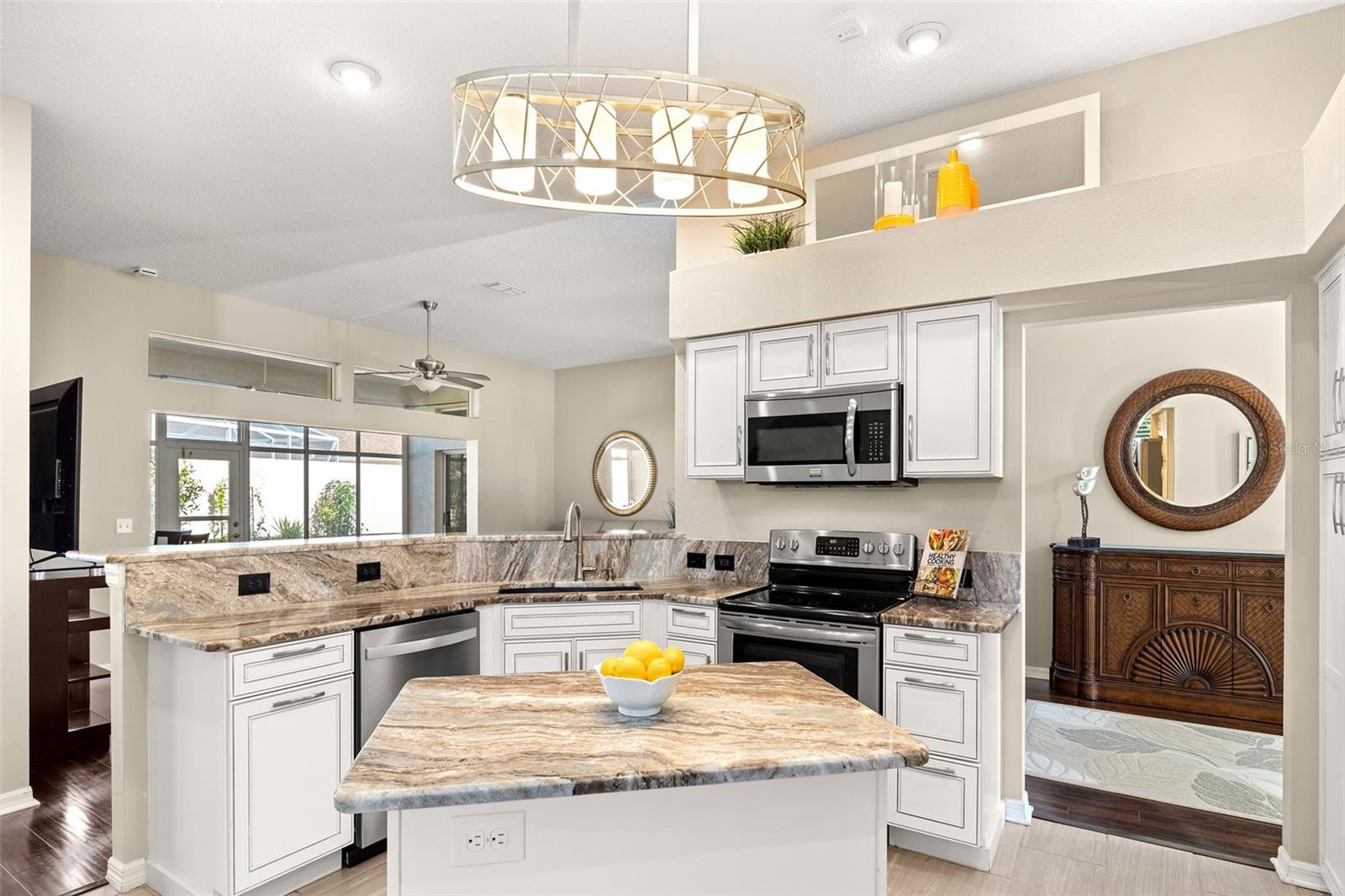 The kitchen has white cabinets with pull outs, GRANITE countertops, dual pantries, stainless steel appliances, and an island with drawers for extra storage.